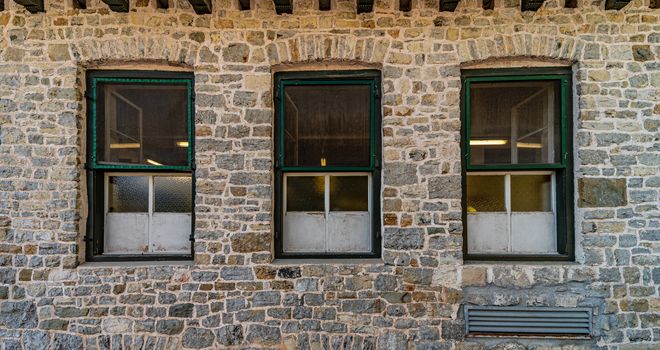 Series of windows lined up on a building of clear stones, mountain architecture