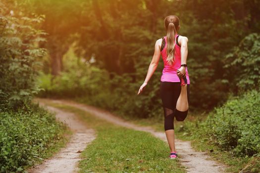 Young fitness woman running in the morning forest trail. Motivation healthy fit living. Running shoe of the person running in nature with beautiful sunlight. Woman warming up before running