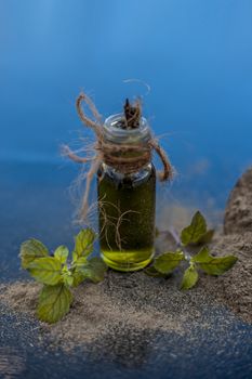 Ayurvedic herb brahmi or Waterhyssop oil in a small transparent glass bottle along with its powder on wooden surface.