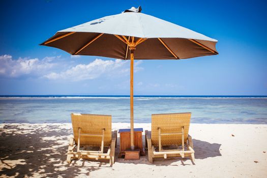 Beach scene with umbrella and deck chairs on a Sanur beach in Bali, Indonesia