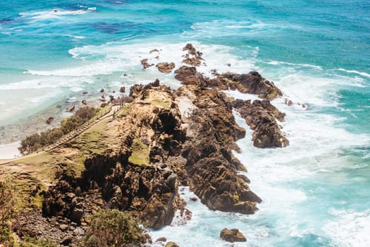 The iconic and famous Byron Bay lighthouse and rocky seascape on a hot autumn day in Byron Bay, New South Wales, Australia.