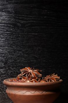 Anis in bowl, dark background, selective focus