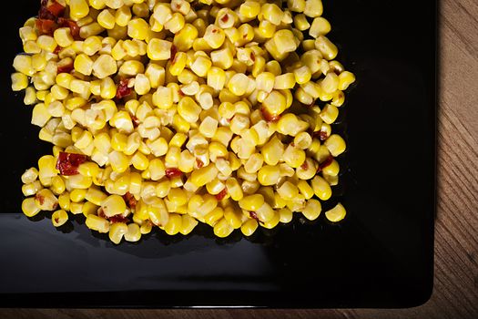 Tinned corn with pepper on a black plate