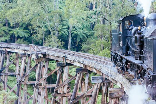 Melbourne, Australia - June 11 2012: Puffing Billy steam train travels across an old wooden bridge in Melbourne, Victoria, Australia