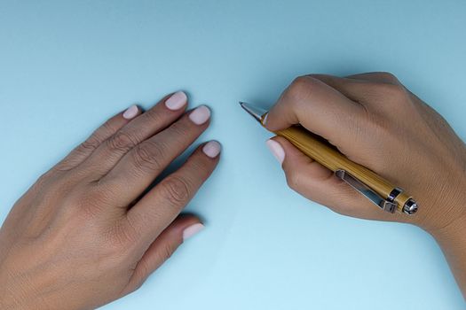 Pen in female hands on a blue background