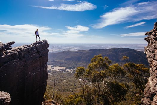 A person being photographed on a rocky ledge from Pinnacle Lookout on the Wonderland hike loop in Victoria, Australia