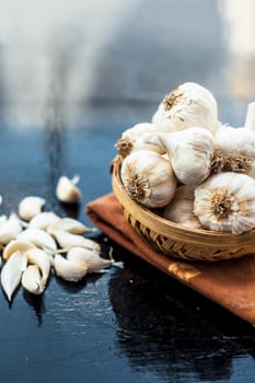 Raw organic garlic bulbs or lasun or Allium sativum in a hamper or basket on wooden surface.