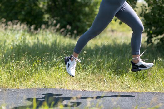 Runner woman in running shoes closeup of woman sporty legs. Female jogging