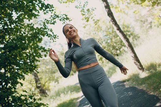 Laughing smiling girl in city park. Young positive woman runner outdoor jogging.