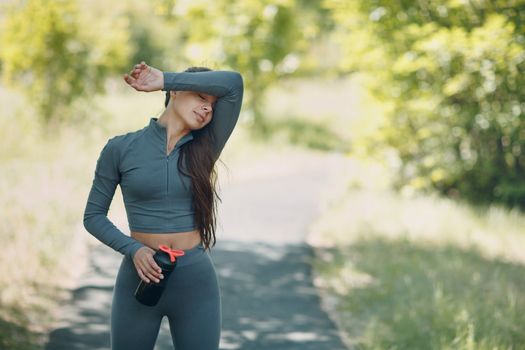 Tired runner woman jogger drinking bottled water after jogging