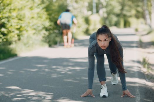 Running girl in city park. Young positive woman runner outdoor jogging.