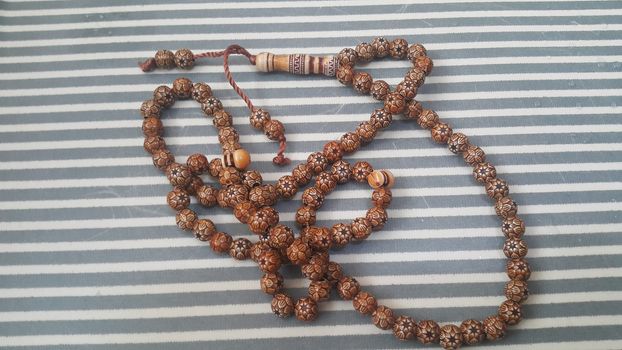 Beautiful wooden prayer beads or rosary with a striped background. Religion concept of ramadan or Eid for muslims.