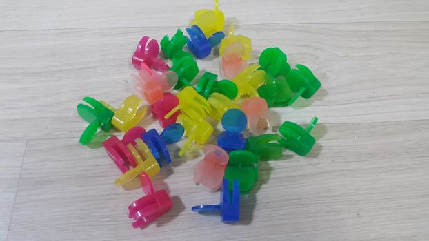 A lot of colorful small holding clips placed on a wooden floor.