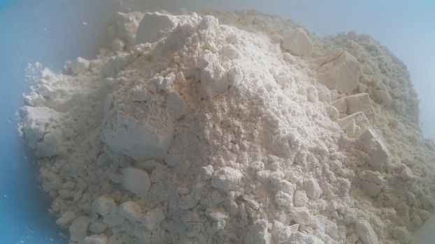 Closeup view of wheat flour heap placed in market for sale. White flour background