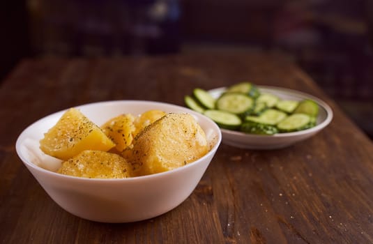 Boiled potatoes with mslom seasonings in a plate on a brown background. High quality photo