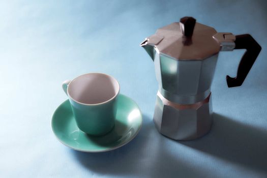 Blue coffee cup and geyser coffee maker stands on a blue background. With copy space. High quality photo