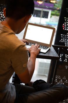 Young entrepreneur SME use notebook showing blank screen with clipping path display  in cafe concept. Hand of business man hold smartphone People use 5G cellular work app with modern internet of things 
