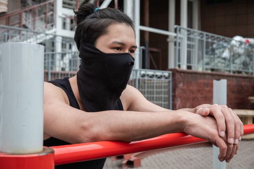 The guy is pushing up on the bars, in a black T-shirt and mask, in quarantine