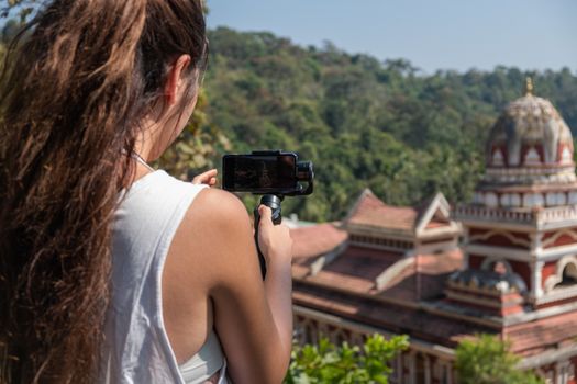 Young woman taking picture of Indian Temple, Goa, India