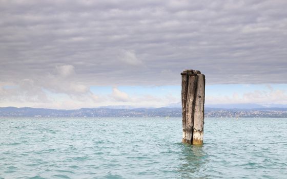 The view past a mooring post on the Sirmione waterfront.  Sirmione is a resort town on the edge of Lake Garda in North East Italy.