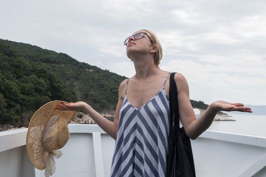 Disappointed female tourist on summer cruss ship vacation, standing on rain and looking angry at overcast cloudy sky. Allways take the weather with you on summer vacations.