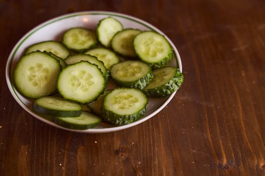 Fresh cucumbers lie in white saucers on a brown background. High quality photo