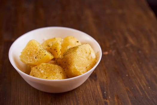 Boiled potatoes with mslom seasonings in a plate on a brown background. High quality photo