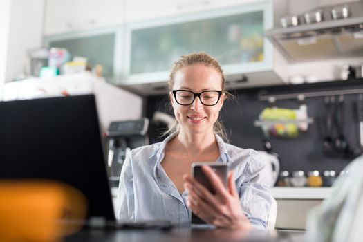 Stay at home and social distancing. Woman in her casual home clothing working remotly from her kitchen dining table in the morning. Video chatting with friend, family or business clients or partners.