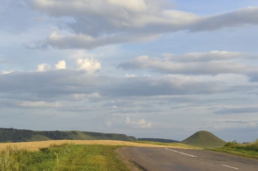 summer landscape with road, mountain and blue sky with clouds