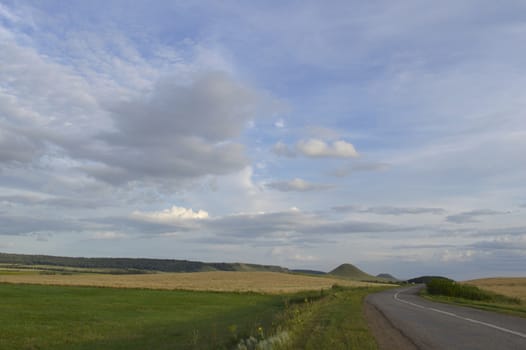 summer landscape with road, mountain and blue sky with clouds