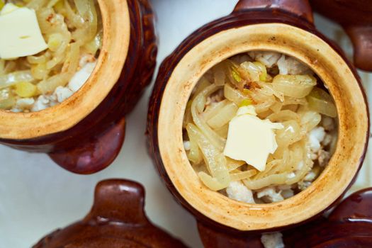 Homemade food. Potatoes and fish in clay pots on a white table. Top view. High quality photo