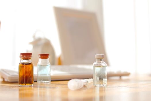 Vaccine bottles placed on a wooden table in a doctor's office.