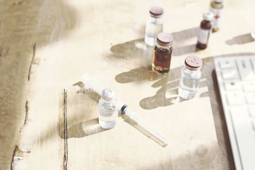 Vaccine bottles placed on a wooden table in a doctor's office.