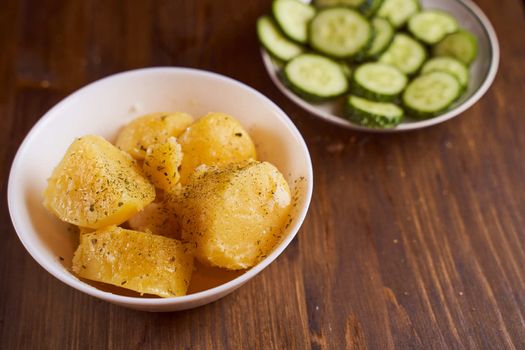 Boiled potatoes with mslom seasonings in a plate on a brown background. High quality photo