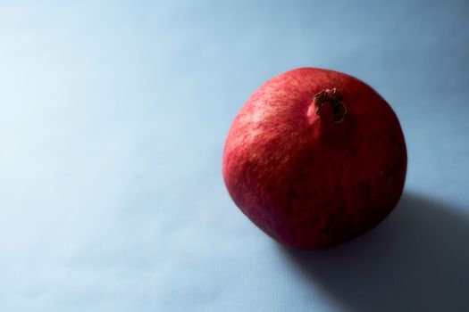 Red ripe pomegranate pours on blue background. High quality photo