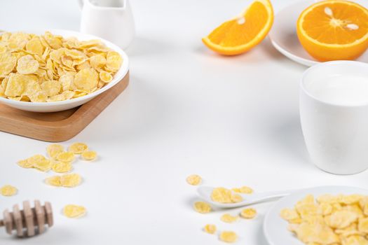 Corn flakes bowl sweeties with milk and orange on white background, close up, fresh and healthy breakfast design concept.