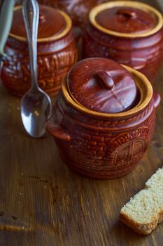 Homemade food. Potatoes and fish in clay pots on a wooden table . High quality photo
