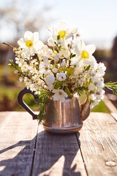 Steel kettle with sprigs of cherry blossoms, pears and apple trees on a natural blurred background. High quality photo
