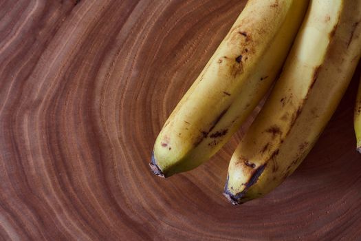 A yellow banana lies on a slice of a tree. Wooden background. High quality photo