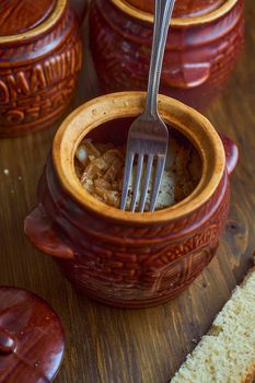 Homemade food. Potatoes and fish in clay pots on a wooden table . High quality photo