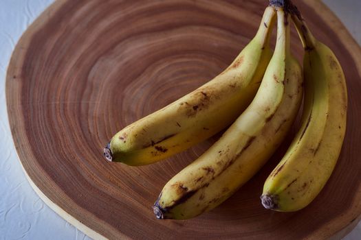 A yellow banana lies on a slice of a tree. Wooden background. High quality photo