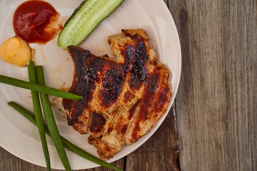 Ready pork steak in a white plate with green onions on an old wooden table. High quality photo