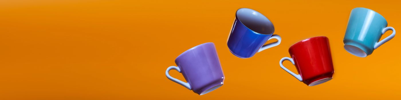 Advertising banner multicolored coffee cups on an orange background. High quality photo