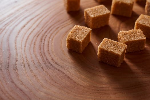 Brown cane sugar pieces on a slice, a plank of wood. High quality photo