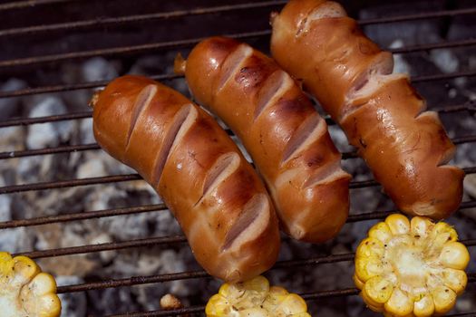 Homemade grilled meat sausages in a white plate on a green background. High quality photo