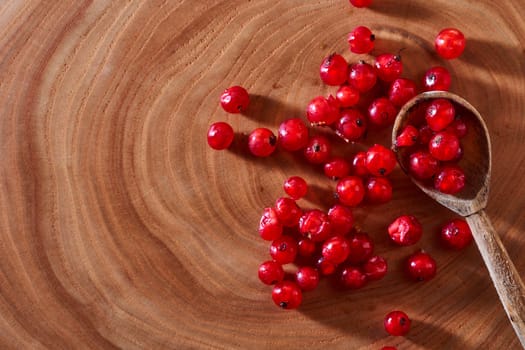  Red currants on wooden background with spoon. Close-up. Top view. High quality photo