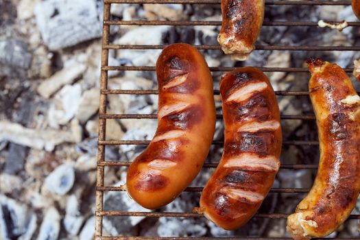 Homemade grilled meat sausages in a white plate on a green background. High quality photo