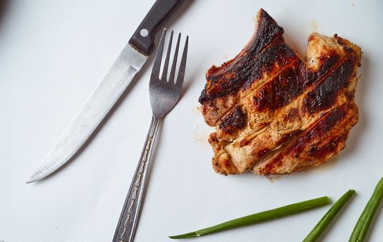 Ready pork steak in a white plate with green onions on a white plate. With copy space. High quality photo