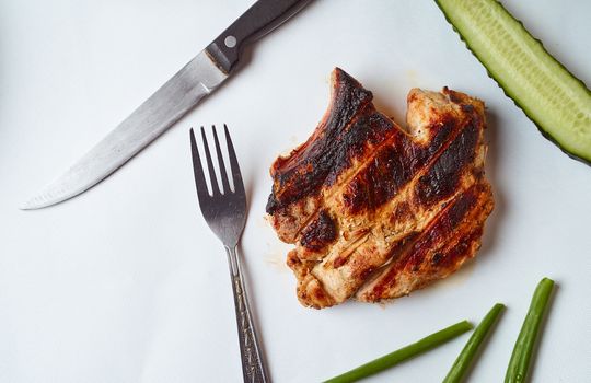 Ready pork steak in a white plate with green onions on a white plate. With copy space. High quality photo