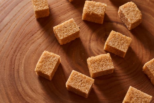 Brown cane sugar pieces on a slice, a plank of wood. High quality photo